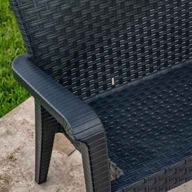 Close-up of a dark wicker chair with a textured surface on a concrete floor.