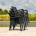 Stack of black outdoor chairs on a wooden deck with a scenic background