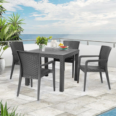 Outdoor patio set with table and chairs on a stone patio by the ocean.