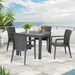Outdoor patio set with table and chairs on a stone patio by the ocean.