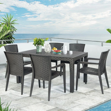 Outdoor dining set with table and chairs on a patio by a pool with ocean view.