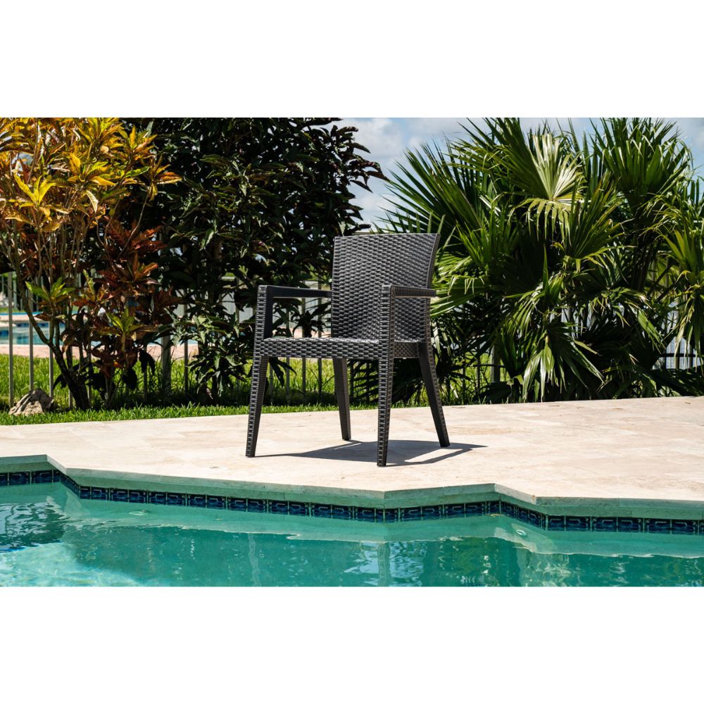 Wicker chair by a pool with greenery in the background