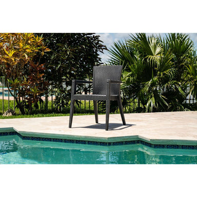 Wicker chair by a pool with greenery in the background