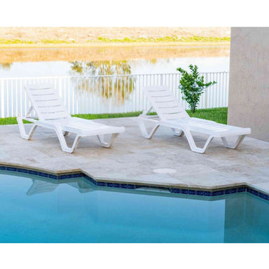 Two white lounge chairs by a pool with a scenic background
