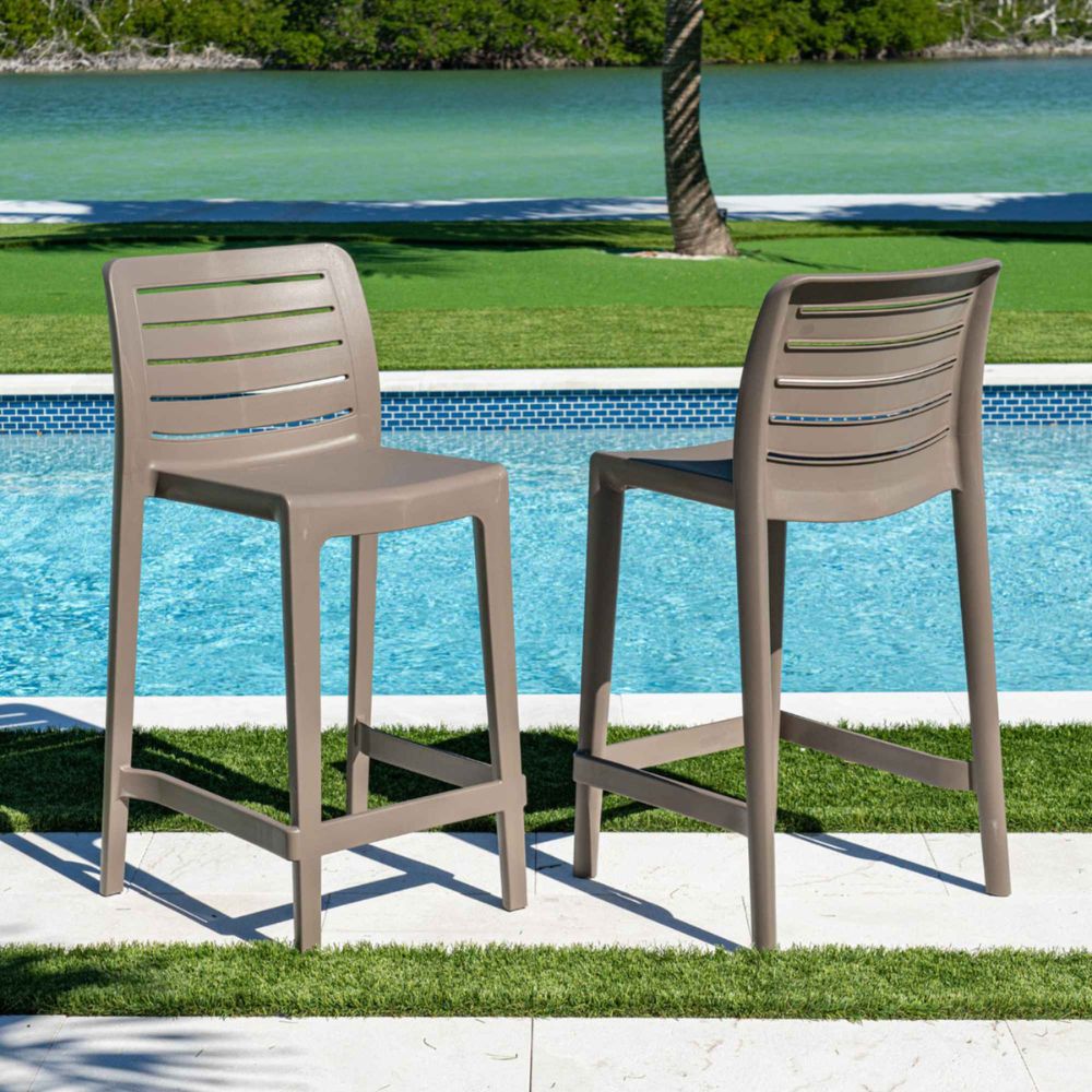 Two outdoor bar stools by a pool with a scenic background