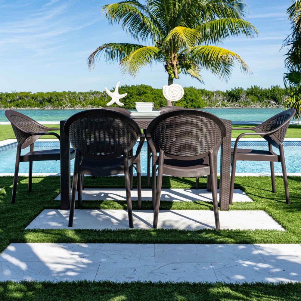 Outdoor dining set with four chairs by a poolside, palm trees in the background