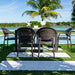 Outdoor dining set with four chairs by a poolside, palm trees in the background