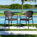 Two brown wicker chairs by a pool with a scenic background