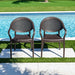 Two brown wicker chairs by a pool with green grass in the background
