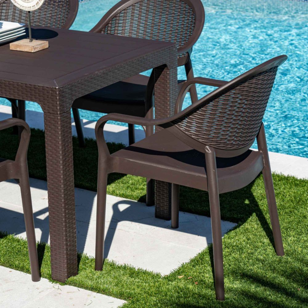 Brown wicker outdoor furniture set with table and chairs by a pool.