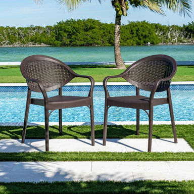 Two brown wicker chairs by a pool with a scenic background
