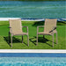 Two beige outdoor chairs on grass near a pool with water in the background